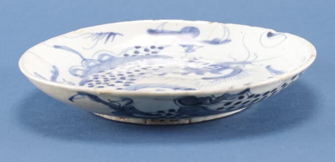 Porseleinen bord met blauwe patronen op blauwe achtergrond.